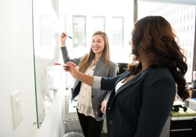 Two colleagues brainstorming at an office whiteboard