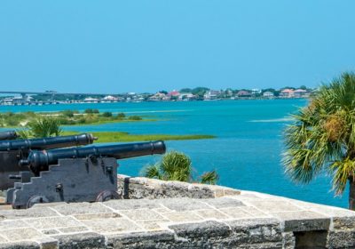 Historic fort cannons overlooking turquoise water and palms